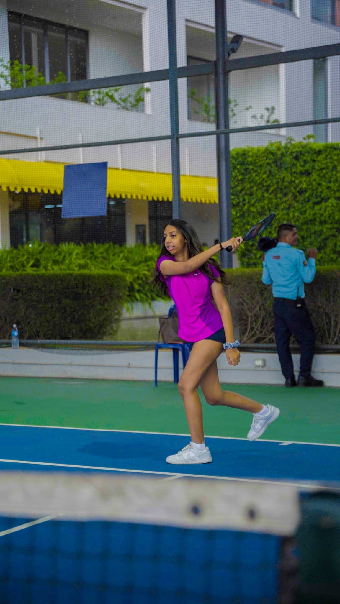 Young girl swinging pickleball paddle on the court, in action during game.